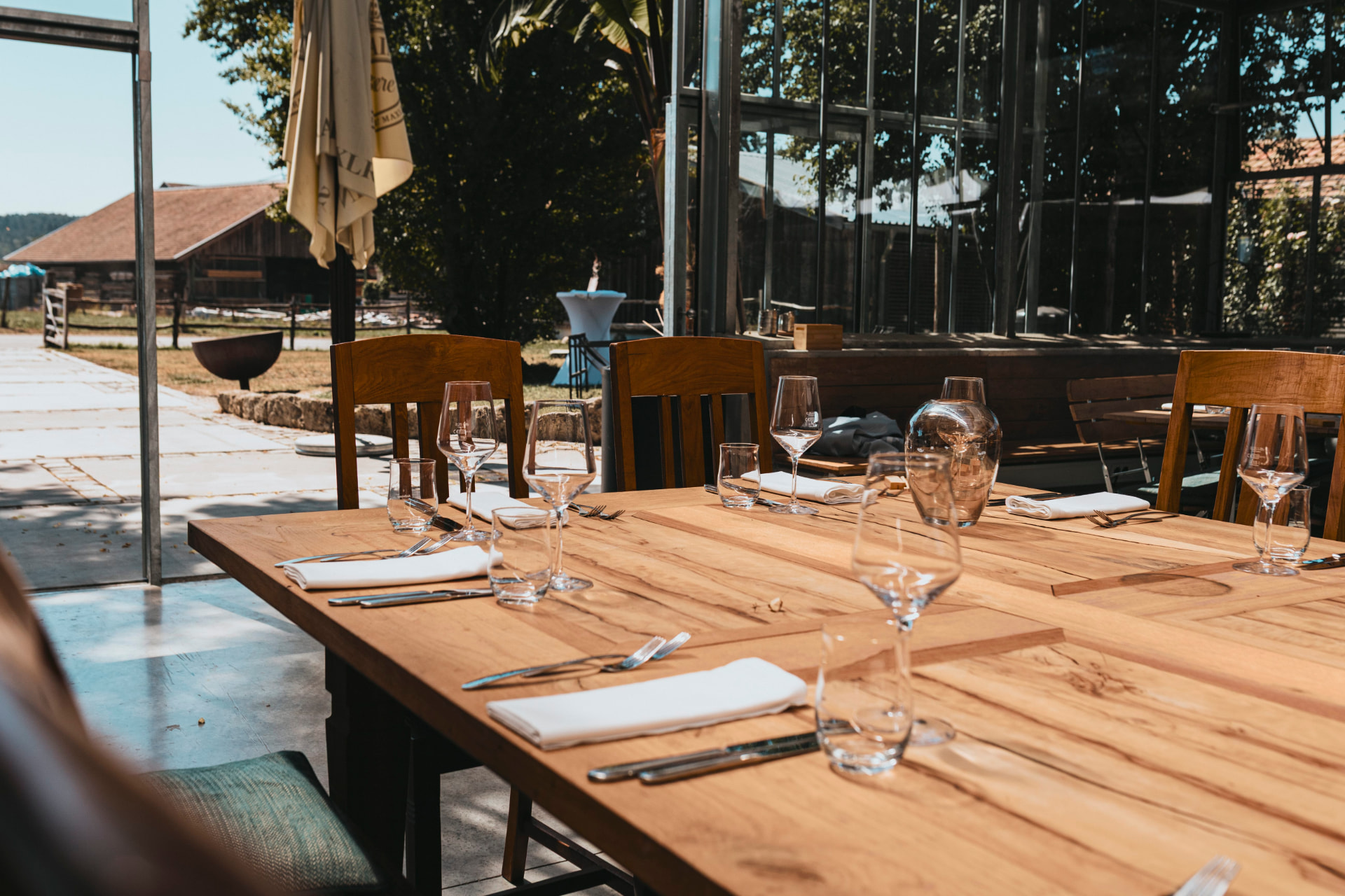 Gedeckter Tisch auf der Terrasse im Abendlicht mit Blick zum Haupthaus
